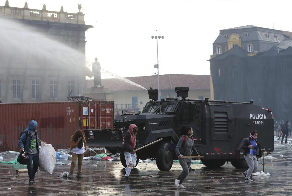 A police water cannon disperses anti-government protesters during a nationwide strike, at Bolivar square in downtown Bogota, Colombia, Thursday, Nov. 21, 2019. Colombia's main union groups and student activists called for a strike to protest the economic policies of Colombian President Ivan Duque government and a long list of grievances. (AP Photo/Fernando Vergara)