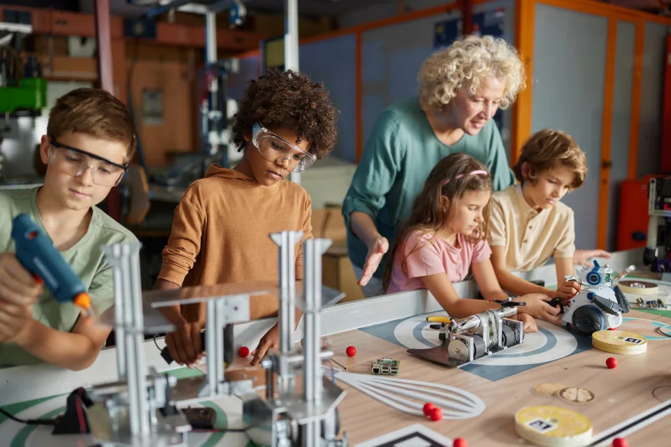 Female teacher assisting little scientists in making a futuristic robot in laboratory.