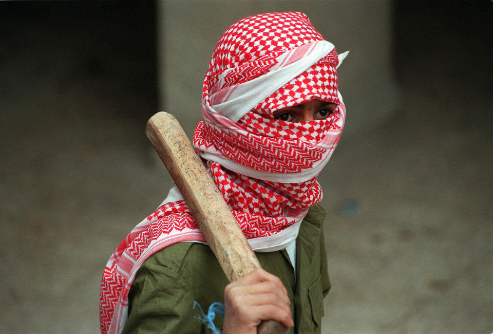 <p>A masked member of the PFLP (Poplular Front for the Liberation of Palestine) carries a club during a demonstration calling for the release of Palestinian prisoners from Israeli jails, Dec. 10, 1998, at Bethlehem University in the West Bank. (Photo: Jacqueline Larma/AP) </p>