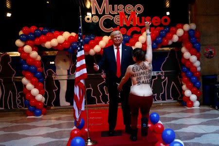 A topless activist from the feminist group FEMEN runs to grab the crotch of a life-sized wax statue of U.S. President-elect Donald Trump during an unveiling ceremony at Madrid's wax museum in Madrid, Spain, January 17, 2017. REUTERS/Susana Vera