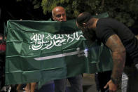 FILE - A Lebanese man kisses a Saudi Arabian flag during a rally in support of the kingdom and against comments made by Lebanon's Information Minister George Kordahi over the war in Yemen, in front of the Saudi Arabia Embassy in Beirut, Lebanon, Oct. 30, 2021. Job opportunities lost and contracts canceled are just some of the ways that ordinary Lebanese have been affected by Saudi Arabia’s furious backlash at Lebanon late last month. (AP Photo/Bilal Hussein, File)