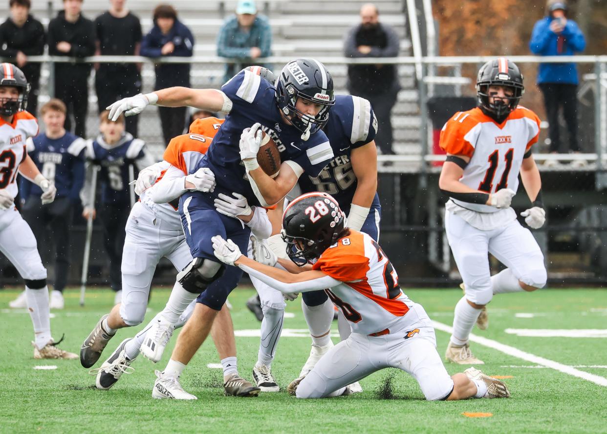 Exeter's Sean DeLello is tackled in the secondary by Keene's Peyton Gowell (10) and Colin Tinnin (28) during Saturday's Division I first-round game.