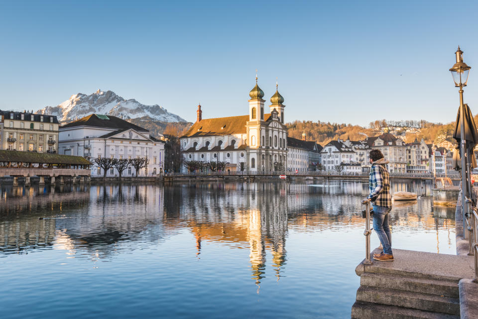 One man looking at the Jesuit Church and Mount Pilatus from the banks of Reuss river in Lucerne, Switzerland