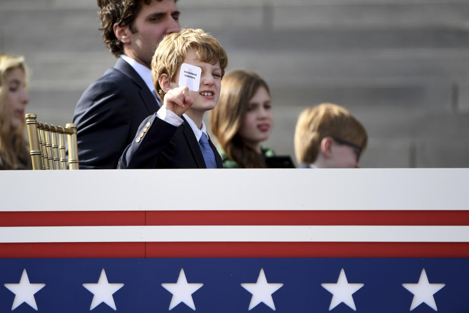 Arkansas Gov. Sarah Huckabee Sanders' son, George, holds a sticker reading "Governor Sanders", as his mother speaks after taking the oath of the office on the steps of the Arkansas Capitol Tuesday, Jan. 10, 2023, in Little Rock, Ark. (AP Photo/Will Newton)