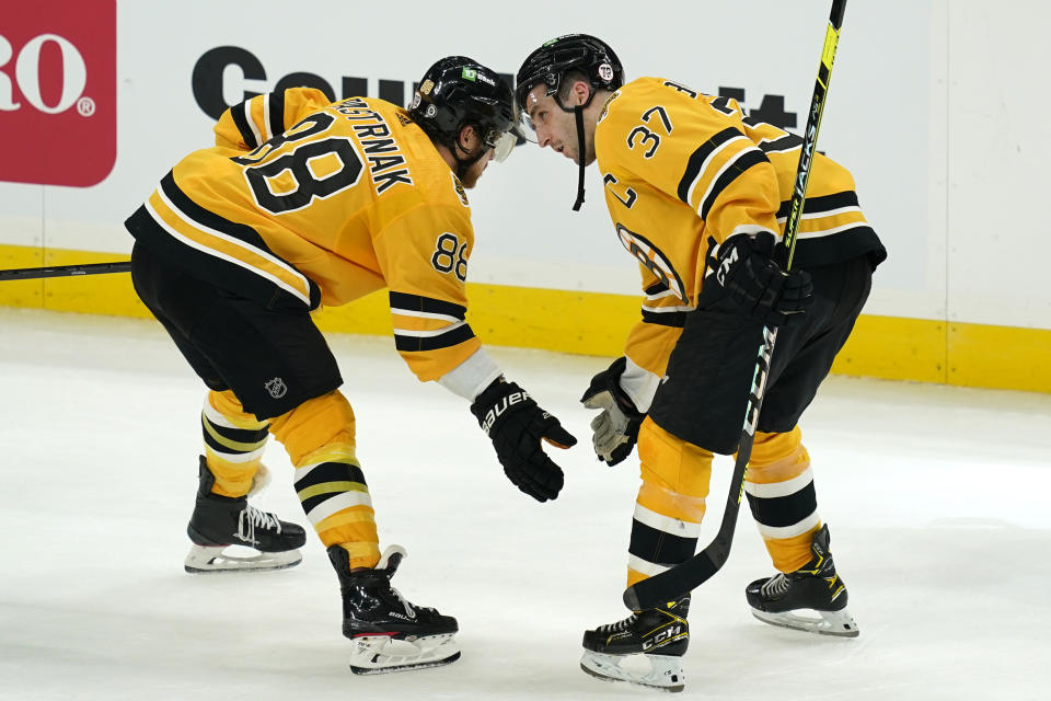 Boston Bruins right wing David Pastrnak (88) and center Patrice Bergeron (37) celebrate after an NHL hockey game against the New York Islanders, Thursday, April 15, 2021, in Boston. (AP Photo/Elise Amendola)