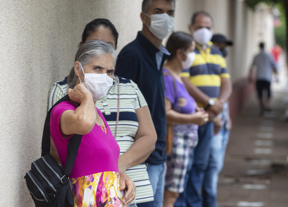 Seventy-year-old Marlene Negrao waits in line outside a public school to get a shot of China's Sinovac CoronaVac vaccine in Serrana, Sao Paulo state, Brazil, Wednesday, Feb. 17, 2021. Brazil's Butantan Institute has started a mass vaccination on Wednesday of the city's entire adult population, about 30,000 people, to test the virus' behaviour in response to the vaccine. (AP Photo/Andre Penner)