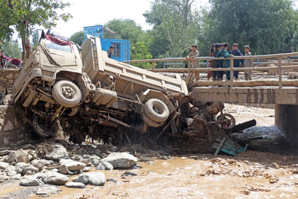 Afghan boys look at a truck that was damaged in flash floods in the Jalrez district of Maidan Wardak province (AFP via Getty Images)