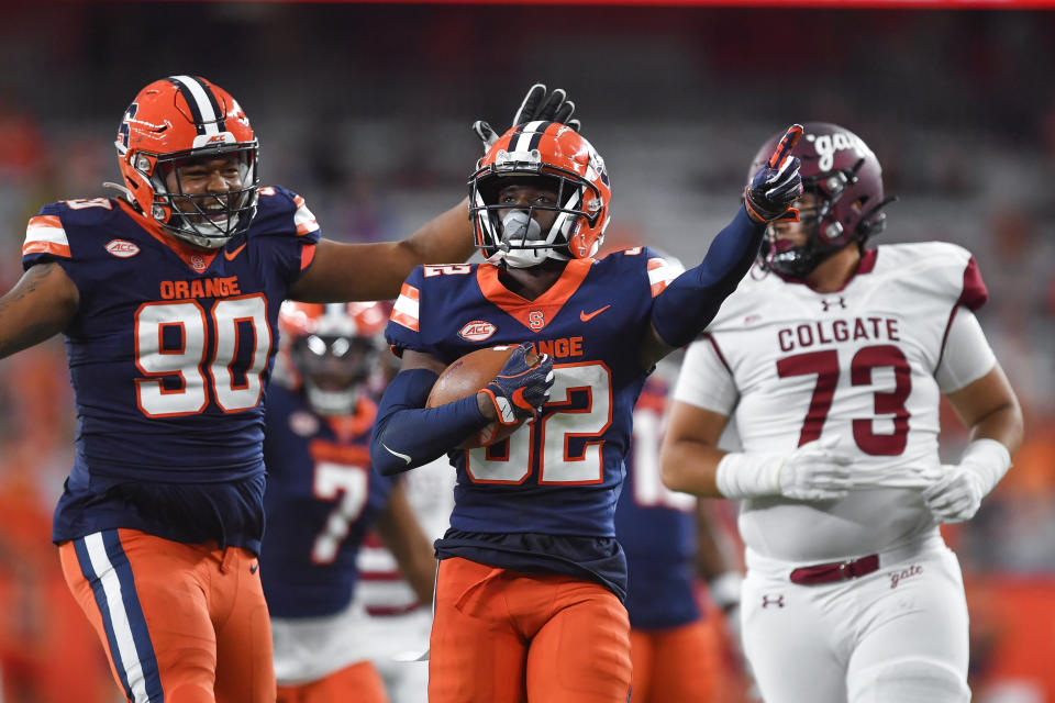 Syracuse defensive back Gregory Delaine, center, celebrates with defensive lineman Terry Lockett (90) after making an interception during the second half of an NCAA college football game against Colgate in Syracuse, N.Y., Saturday, Sept. 2, 2023. (AP Photo/Adrian Kraus)