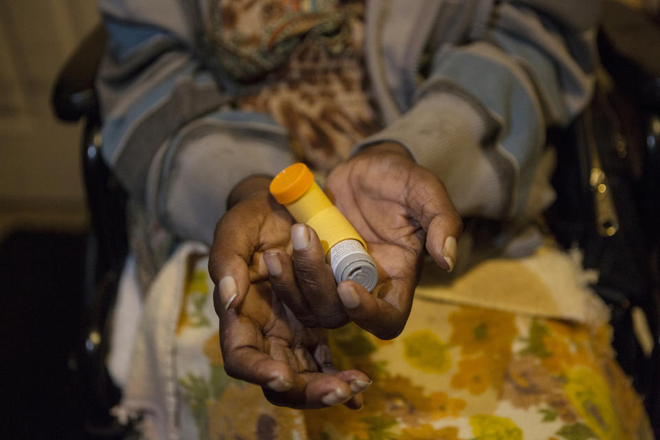 In this Nov. 4, 2019 photo, Annie Young, who suffers from asthma, shows her inhaler at her home in Pahokee, Fla. Patterson says that smoke from sugar cane burns triggers her asthma, making it difficult to breathe. For generations, Florida's sugar cane farmers have legally set fire to their fields prior to harvest. The smoke is a nuisance for predominantly poor communities near the fields, and the practice is being phased out due to health concerns. (AP Photo/Ellis Rua)