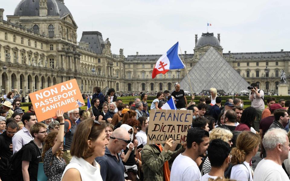 A protester holds a placard at a protest against mandatory vaccination and health passports outside the Louvre Museum in Paris, France on 17 July 2021 - Bertrand Guay/AFP