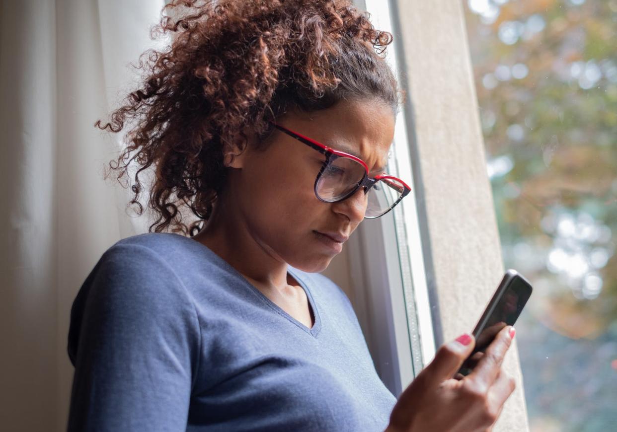 <span class="caption">Have some healthy skepticism when you encounter images online.</span> <span class="attribution"><a class="link " href="https://www.gettyimages.com/detail/photo/sad-black-woman-near-window-reading-phone-message-royalty-free-image/1054665140" rel="nofollow noopener" target="_blank" data-ylk="slk:tommaso79/Stock via Getty Images Plus;elm:context_link;itc:0;sec:content-canvas">tommaso79/Stock via Getty Images Plus</a></span>