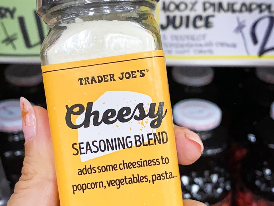 hand holding container of cheesy seasoning blend at trader joes