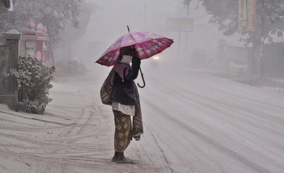 A women walks on a road covered with volcanic ash following an eruption of Mount Kelud, in Yogyakarta, Indonesia, Friday, Feb 14, 2014. Volcanic ash from a major eruption in Indonesia shrouded a large swath of the country's most densely populated island on Friday, closed three international airports and sent thousands fleeing. (AP Photo/Slamet Riyadi)