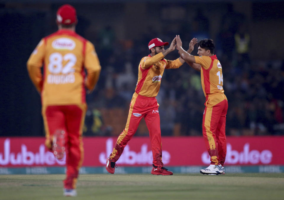 Islamabad United pacer Muhammad Musa, right, celebrates with teammate Shadab Khan after taking the wicket of Lahore Qalandars batsman Chris Lynn during their Pakistan Super League T20 cricket match, at Gaddafi Stadium in Lahore, Pakistan, Sunday, Feb. 23, 2020. (AP Photo/K.M. Chaudary)