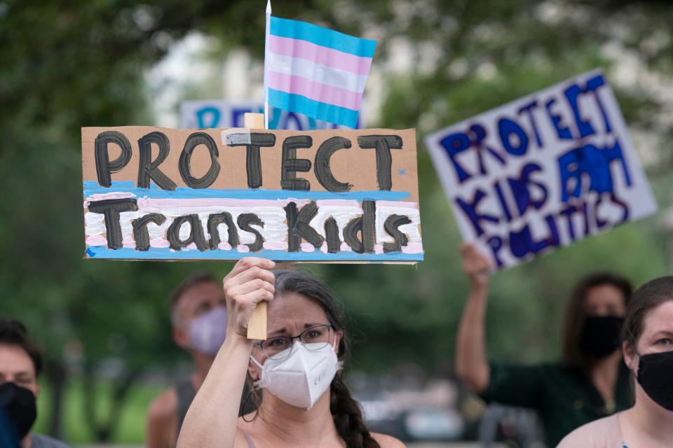 A demonstrator holds a sign in support of transgender youth.