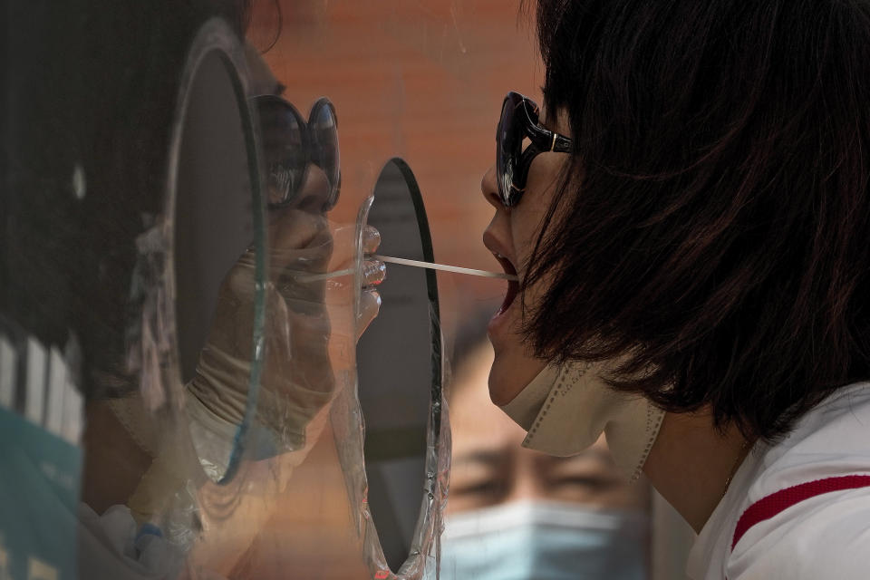 A woman gets her routine COVID-19 throat swab at a coronavirus testing site in Beijing, Tuesday, Aug. 23, 2022. (AP Photo/Andy Wong)