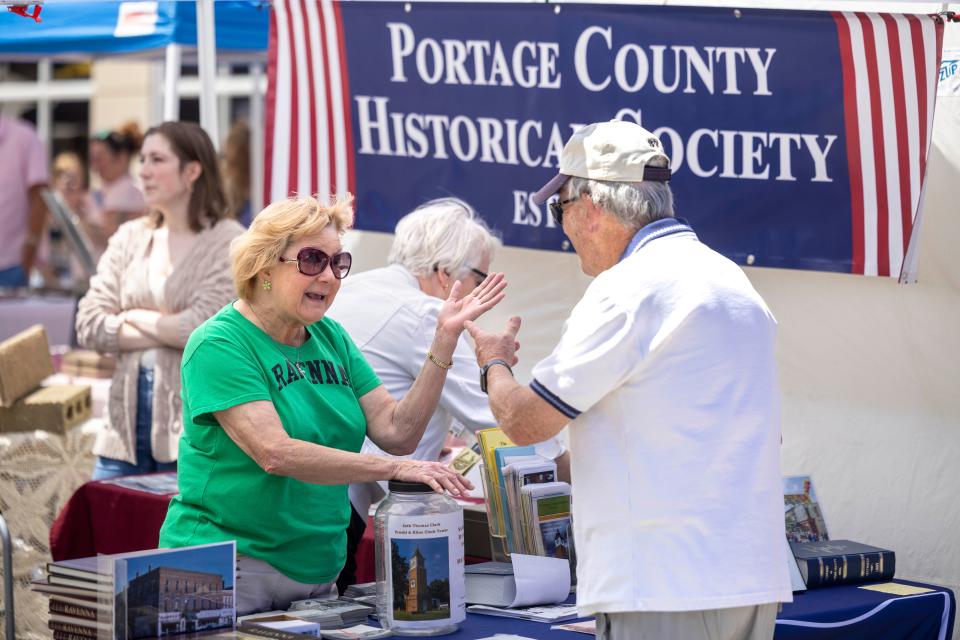 Sarah Jones, a volunteer with the Portage County Historical Society, talks to visitors to the Ravenna 225th Birthday Celebration and Art on Main arts & crafts show held Saturday, June 8, 2024, in downtown Ravenna.