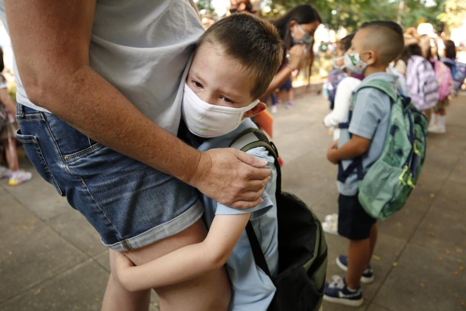 A young boy hugs his mother's legs