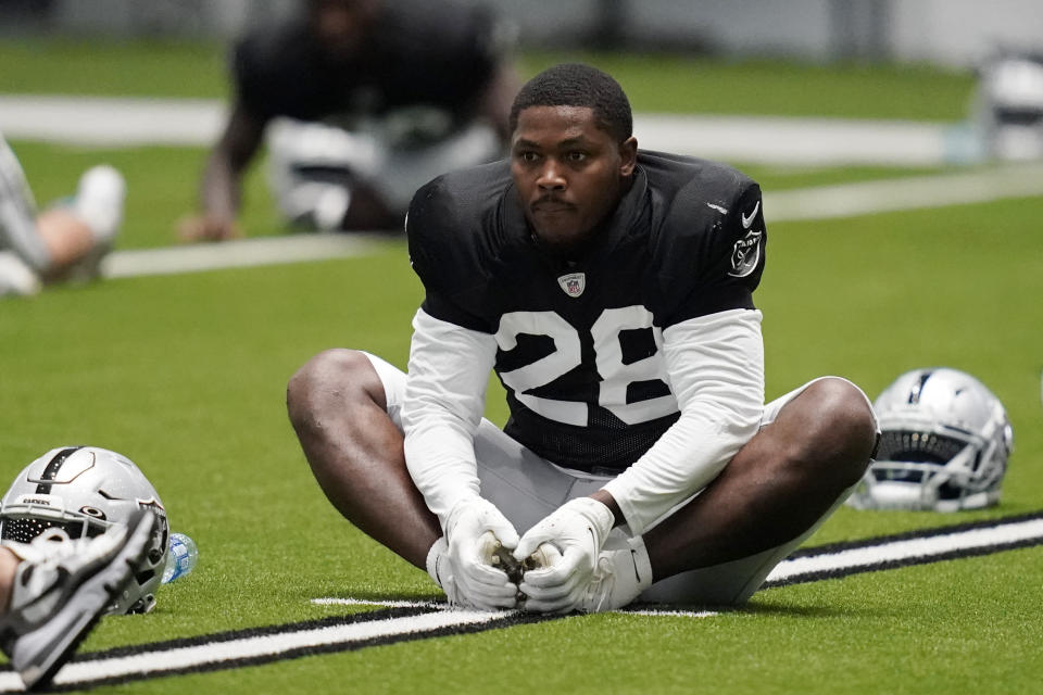 Las Vegas Raiders running back Josh Jacobs (28) stretches during an NFL football training camp practice Tuesday, Aug. 18, 2020, in Henderson, Nev. Speedy receiver Henry Ruggs III was drafted 12th overall, teaming with breakout tight end Darren Waller, versatile back Josh Jacobs and slot receiver Hunter Renfrow to give the team its most complete offense since coach Jon Gruden returned in 2018. (AP Photo/John Locher, Pool)