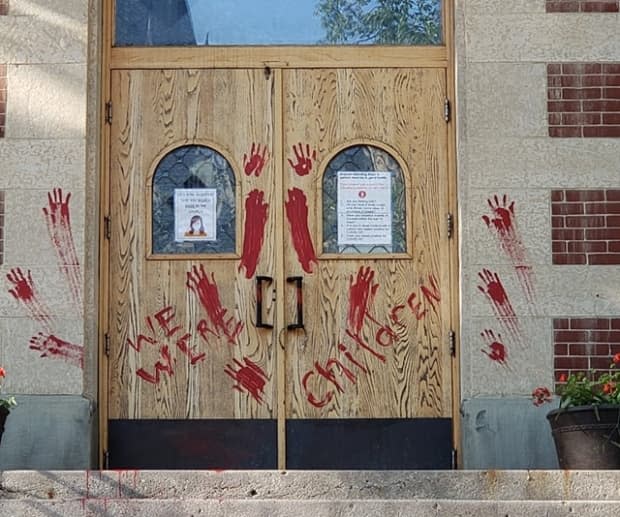 The doors of Saskatoon's St. Paul's Co-Cathedral were painted in protest after the discovery of 751 unmarked graves near the former Marieval Residential School on the Cowessess First Nation in June. (Donna Heimbecker/Facebook - image credit)