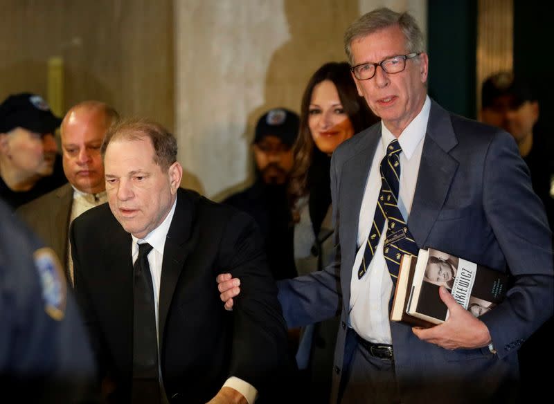 Man holds books as he escorts film producer Harvey Weinstein to court in New York