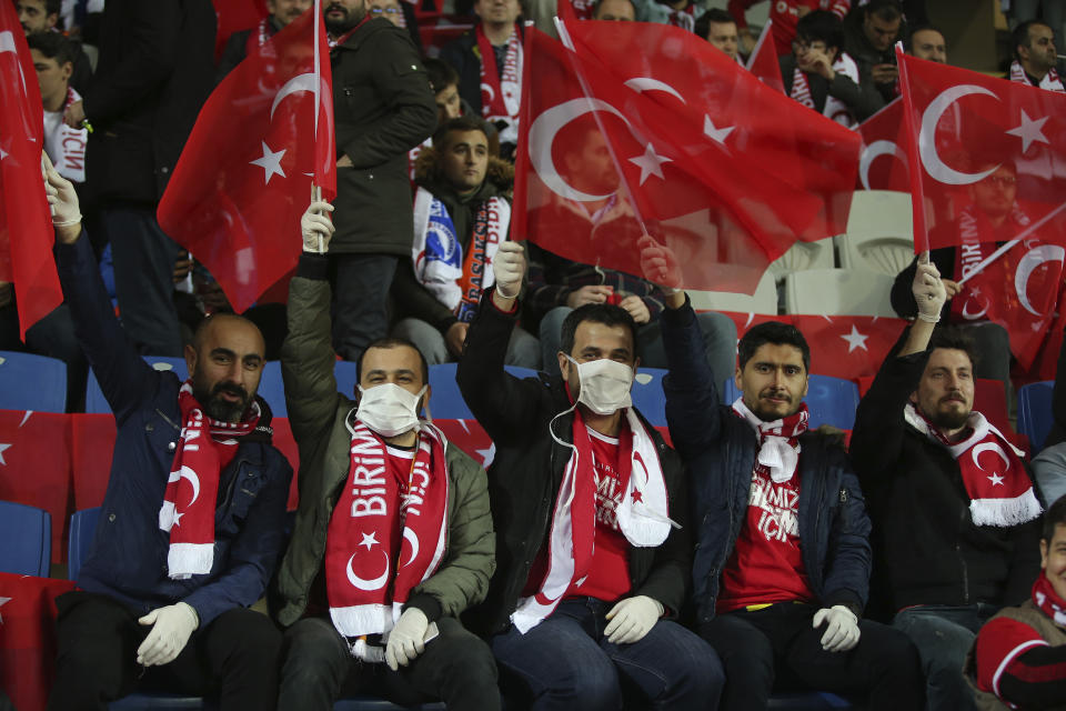 FILE - In this Thursday, March 12, 2020 file photo spectators, some wearing masks because of the coronavirus outbreak, wave Turkish flags prior to a Europa League top 16 first leg soccer match between Basaksehir and Copenhagen, in Istanbul. (AP Photo, File)