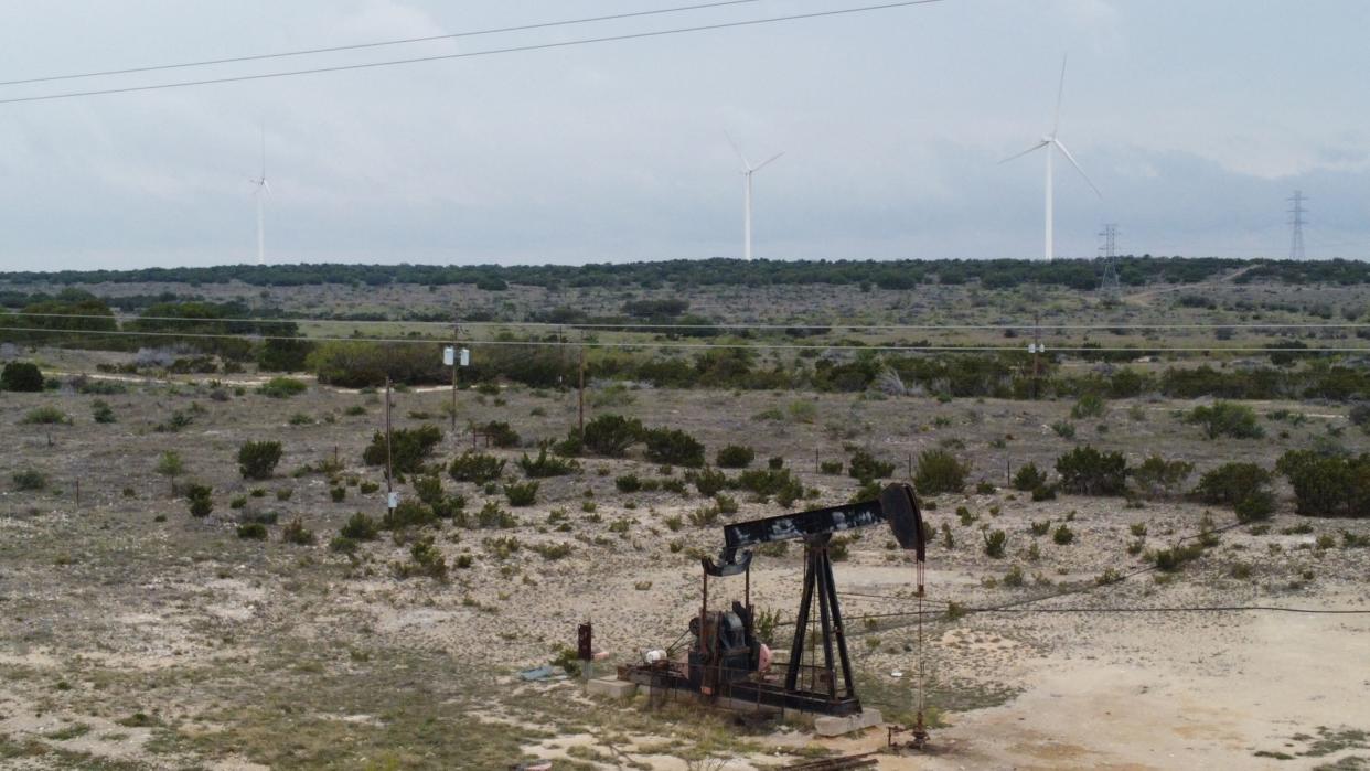 Blades from wind turbines rotate in a field behind an out-of-use oil pumpjack last month near Eldorado, Texas. (Photo: FRANCOIS PICARD via Getty Images)