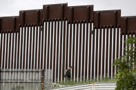 A border patrol agent walks along a border wall separating Tijuana, Mexico, from San Diego, Wednesday, March 18, 2020, in San Diego. (AP Photo/Gregory Bull)