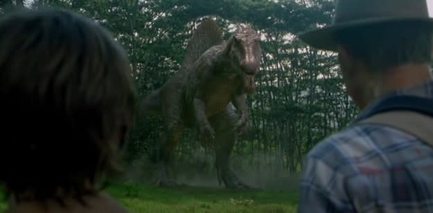 Spinosaurus looks at two people in the wild
