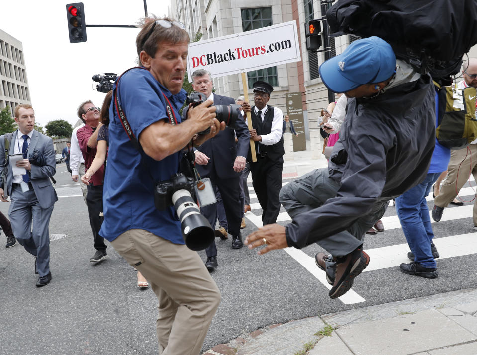 Attorney Kevin Downing, center, with the defense team for Paul Manafort, watches as television cameraman Chris Plater, trips and falls backwards outside of federal court in Washington, Friday, Sept. 14, 2018. Former Trump campaign chairman Paul Manafort has pleaded guilty to two federal charges as part of a cooperation deal with prosecutors. The deal requires him to cooperate "fully and truthfully" with special counsel Robert Mueller's Russia investigation. The charges against Manafort are related to his Ukrainian consulting work, not Russian interference in the 2016 presidential election.(AP Photo/Pablo Martinez Monsivais)