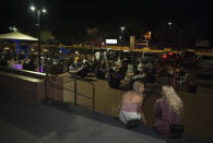 People sit outside a terrace bar in Fuengirola, near Malaga, Spain, Saturday, Aug. 8, 2020. The increase in Spain of coronavirus outbreaks associated with nightlife has set off alarms in recent days, mainly in tourist areas where pubs and discos are full before the summer tourist campaign. (AP Photo/Jesus Merida)