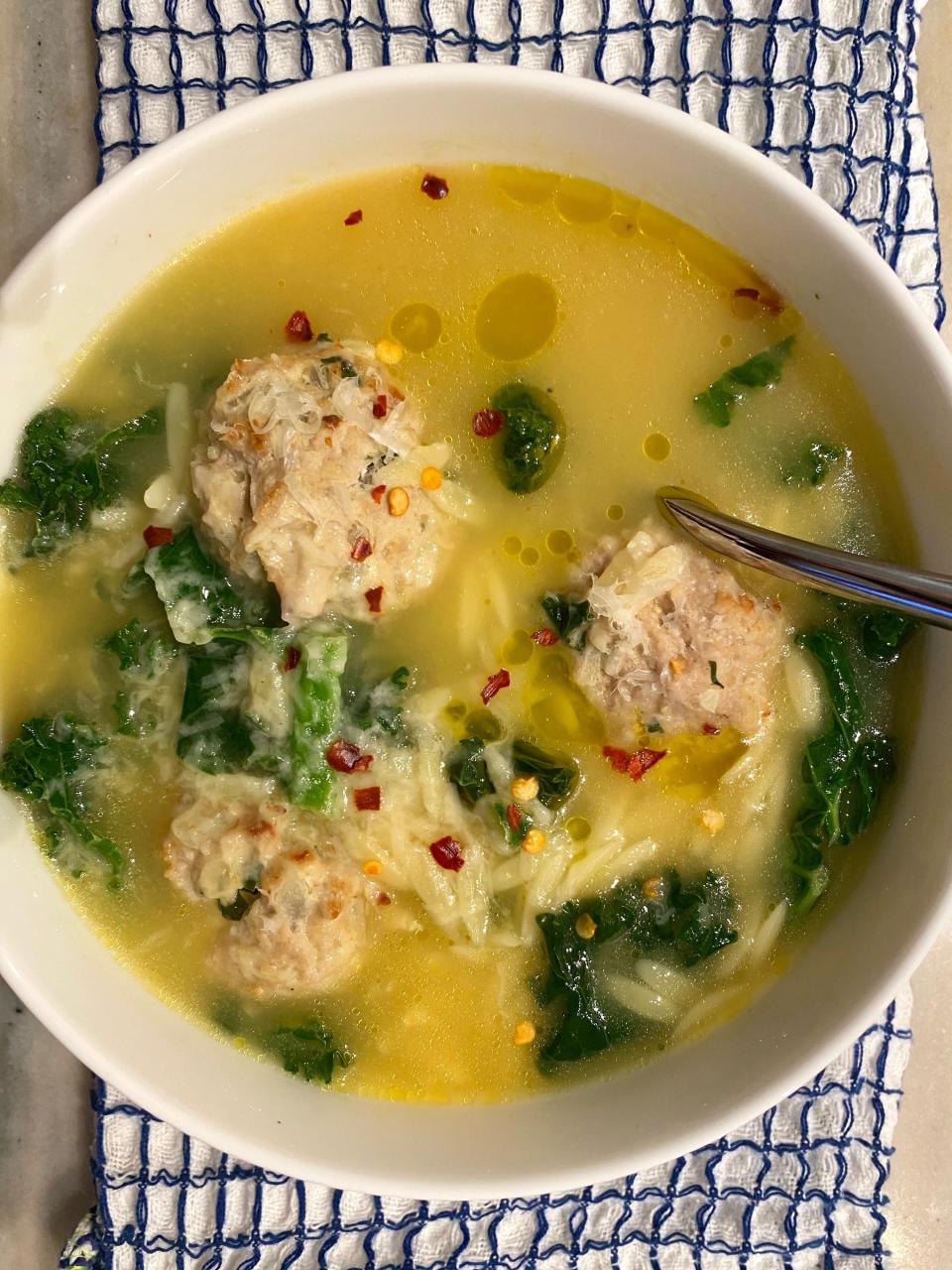 A bowl of soup with red pepper flakes.