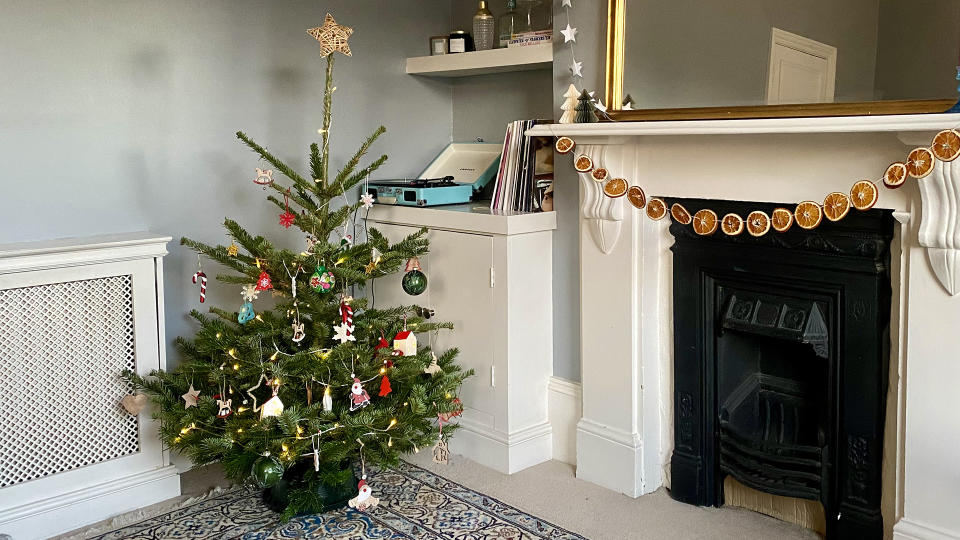 Christmas tree with lights on next to a fireplace.