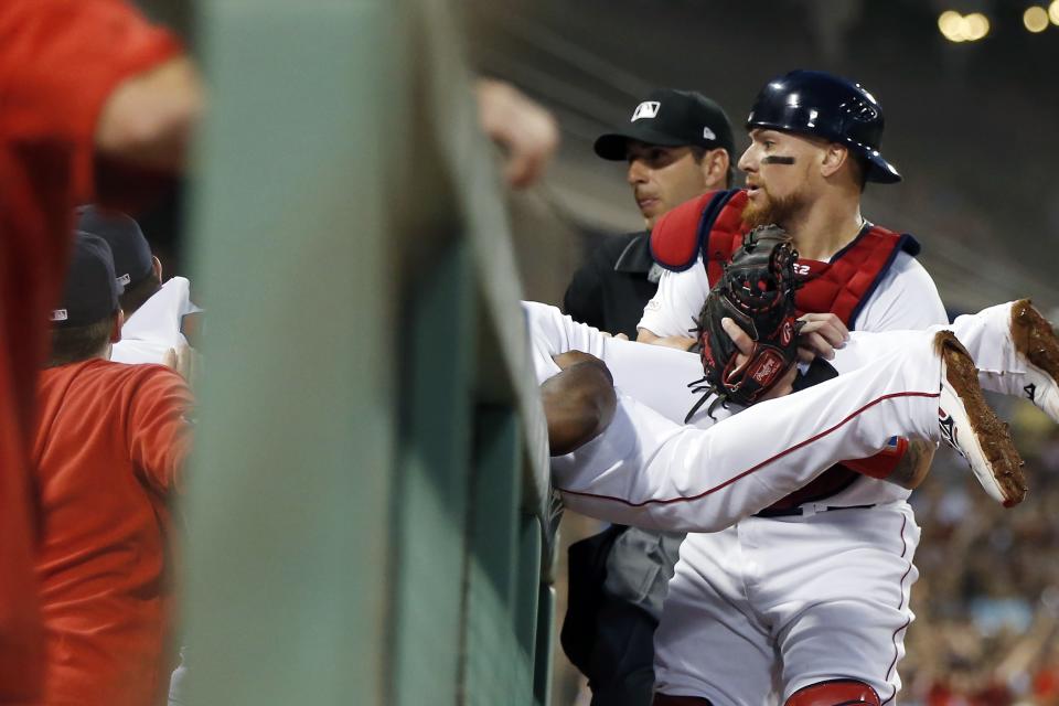 Boston Red Sox's Michael Chavis makes a catch on a pop foul by Los Angeles Dodgers' Enrique Hernandez over the dugout rail as Christian Vazquez, right, holds his legs during the fourth inning of a baseball game in Boston, Sunday, July 14, 2019. (AP Photo/Michael Dwyer)