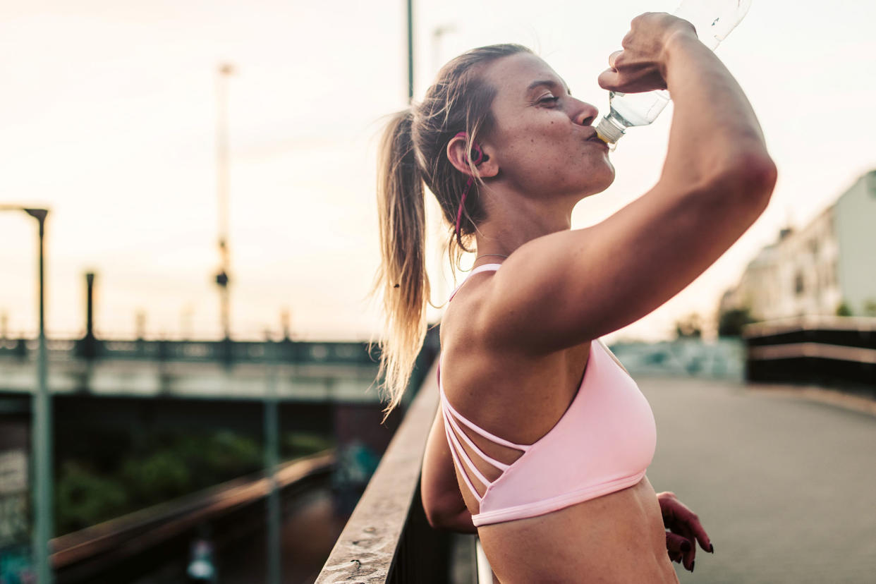 Woman after fitness workout,drinking outdoor in the city.