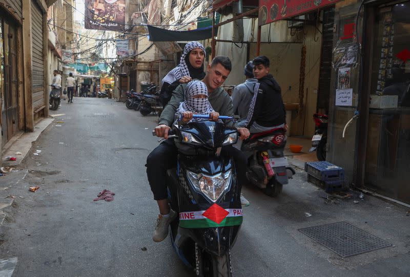 People wearing keffiyehs ride on a motorbike during a global call for strike in solidarity with Gaza and Palestinian people, at Burj al-Barajneh refugee camp in Beirut