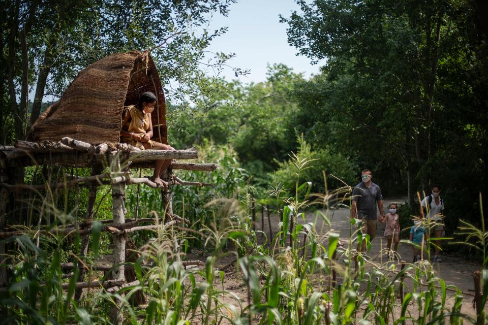Alyssa Harris, a member of the Mashpee Wampanoags and a museum educator at Plimoth Patuxet Museums sits in a corn watch tower as visitors walk through the Wampanoag Homesite living history exhibit, Wednesday, Aug. 12, 2020, in Plymouth.