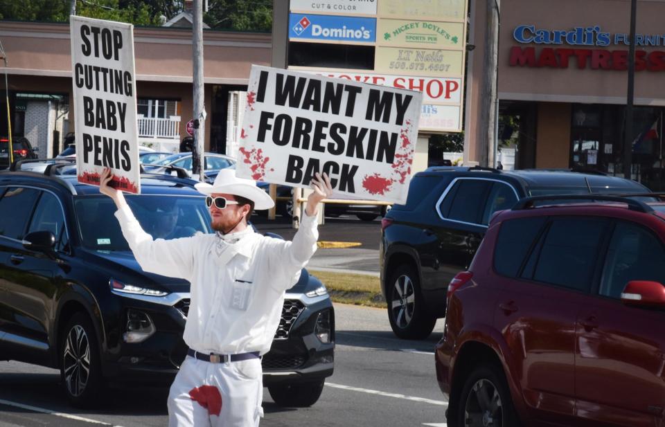 David Atkinson, spokesperson for the Bloodstained Men, holds signs and wears graphic clothing to make his opposition to circumcision clear on Tuesday.