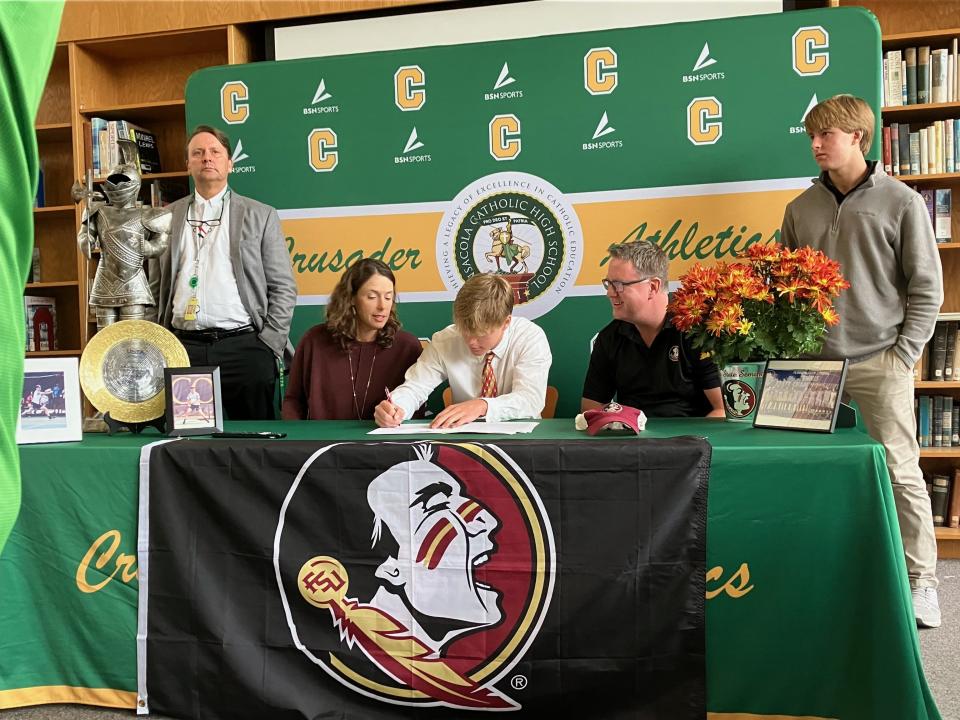 Sitting in between his mother Jennifer Lyons and father Tommy Lyons and with head coach Geoff Watts (far left) and younger brother Conner Lyons standing along side, Pensacola Catholic senior Justin Lyons signs his letter of intent to play tennis for Florida State University on Thursday, Nov. 10, 2022 from the Pensacola Catholic High School media center.