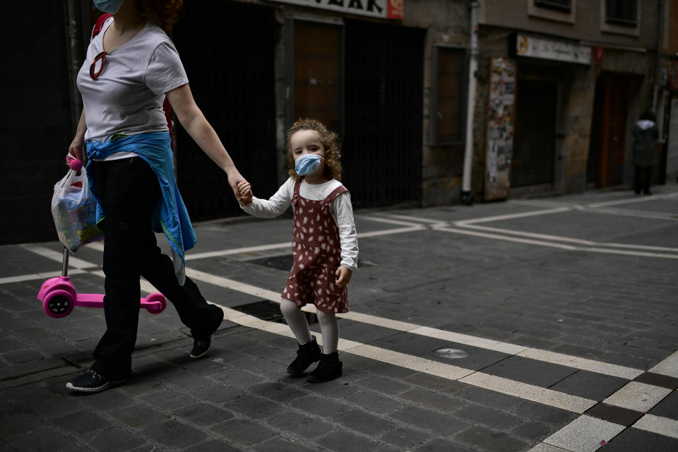 Irati, a little girl, 3 years old, wears face mask to prevent the coronavirus while she's going for a walk with her mother, Montse Fernandez , in Pamplona, northern Spain, Sunday, April 27, 2020. On Sunday, children under 14 years old will be allowed to take walks with a parent for up to one hour and within one kilometer from home, ending six weeks of compete seclusion. (AP Photo/Alvaro Barrientos)