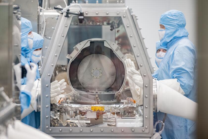 Workers at NASA's Johnson Space Center in Houston remove the lid of the OSIRIS-REx sample return canister.