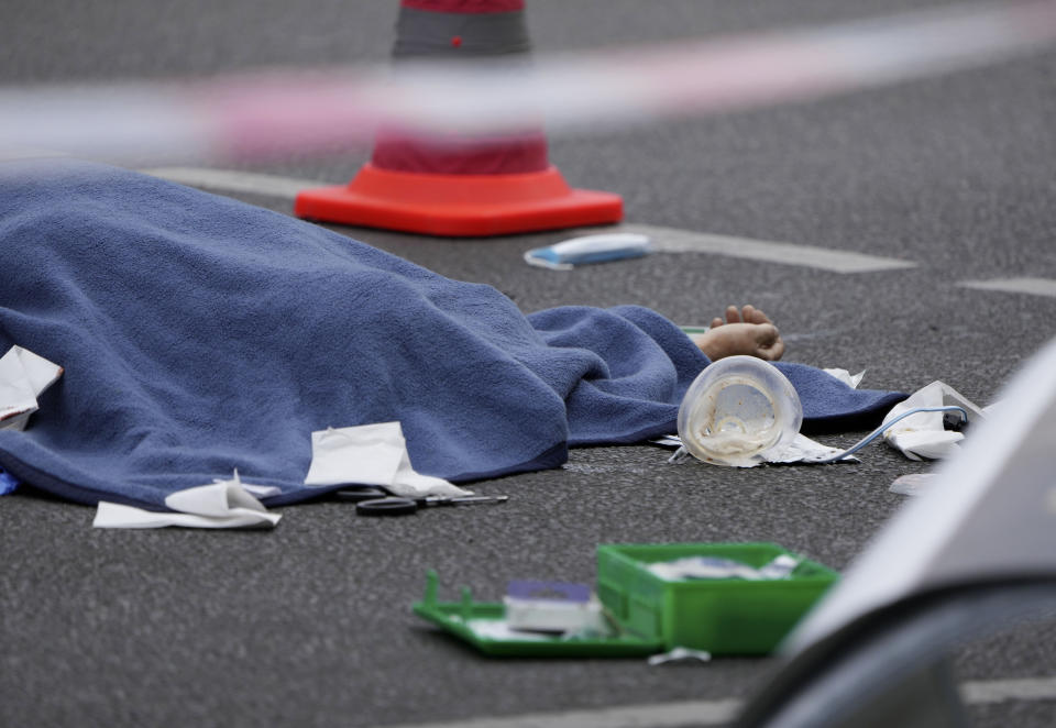 A covered body lies on the street after a car crashed into a crowd of people in central Berlin, Germany, Wednesday, June 8, 2022. (AP Photo/Michael Sohn)
