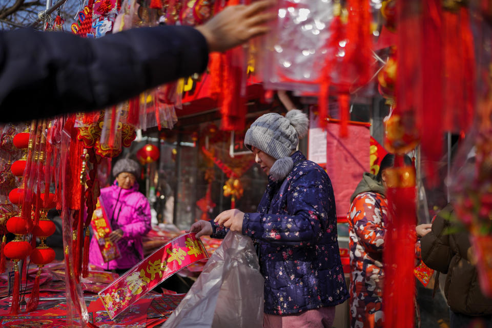 Residents shop for prosperity decorations on the eve of the Chinese Lunar New Year, at a pavement shop in Beijing, Friday, Feb. 9, 2024. (AP Photo/Andy Wong)