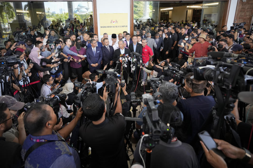 Malaysia's former Prime Minister Muhyiddin Yassin, center, speaks to media outside courthouse, after charged with corruption and money laundering, in Kuala Lumpur, Malaysia, Friday, March 10, 2023. Muhyiddin has been charged with corruption and money laundering, making him Malaysia's second ex-leader to be indicted after leaving office. Muhyiddin pleaded innocent Friday to four charges of corruption and two charges of money laundering. (AP Photo/Vincent Thian)