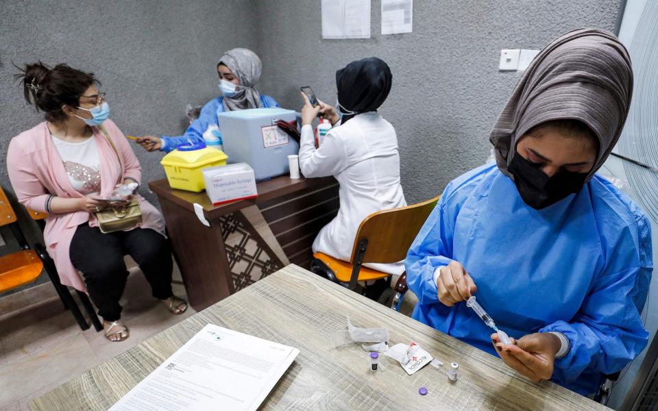 A nurse prepares a dose of the Pfizer-BioNTech COVID-19 coronavirus vaccine while another administers one at a vaccination centre in the Kindi Hospital in Iraq's capital Baghdad - AHMAD AL-RUBAYE / AFP