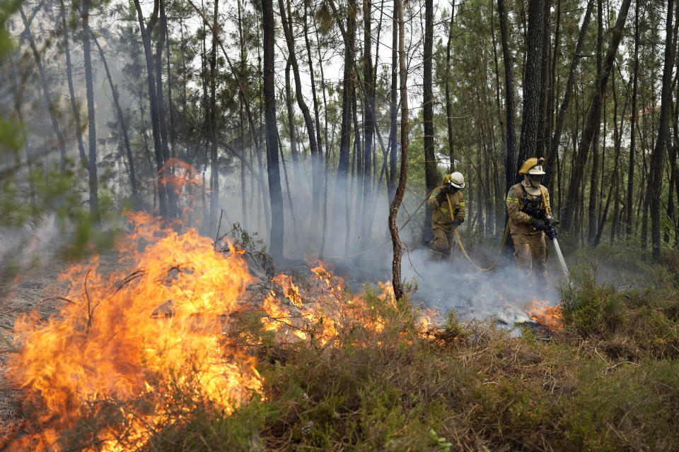 National Republican Guard firefighters put out a forest fire in the village of Rebolo, near Ansiao central Portugal, Thursday, July 14, 2022. Thousands of firefighters in Portugal have been battling fires all over the country that forced the evacuation of dozens of people from their homes. (AP Photo/Armando Franca)