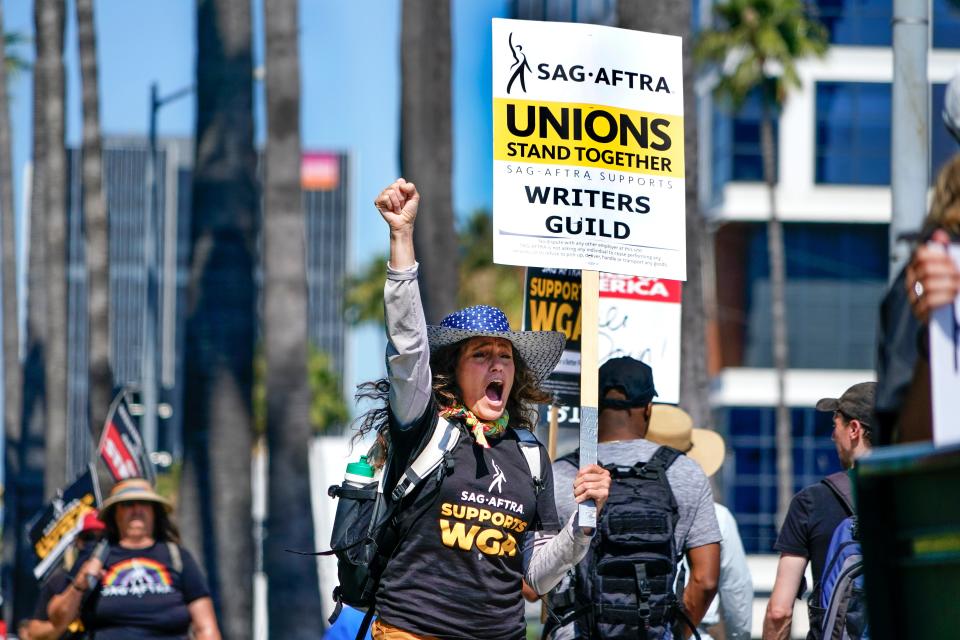 Christine Robert, a member of SAG-AFTRA, pumps her fist and yells at honking motorists on Sunset Boulevard. Members of the actors' union and the writers' union, the WGA, picket outside Netflix offices on July 12, 2023. SAG-AFTRA is preparing to go out on strike at midnight.