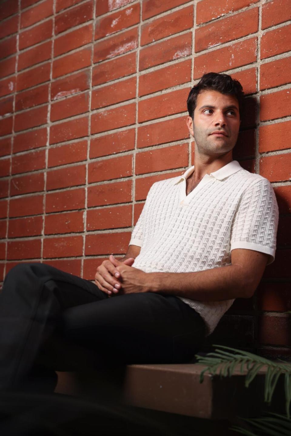 A man sits on a couch against a brick wall.