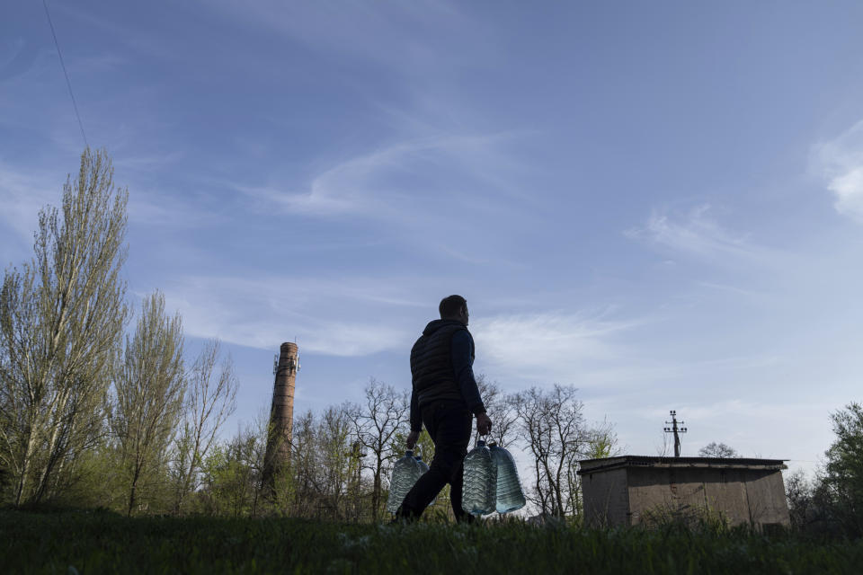 Andriy Cheremushkin carries cans with water in Toretsk, eastern Ukraine, Monday, April 25, 2022. Toretsk residents have had no access to water for more than two months because of the war. (AP Photo/Evgeniy Maloletka)