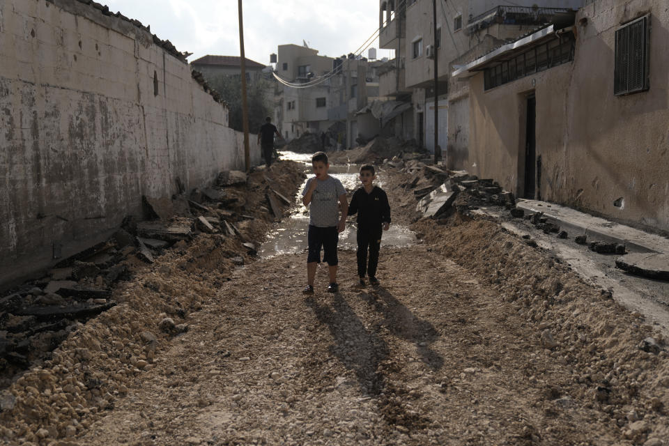 Palestinian children walk through a street destroyed in an Israeli army raid on Jenin, West Bank, Friday, Nov. 3, 2023. (AP Photo/Majdi Mohammed)